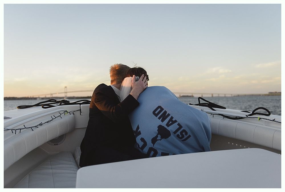 Couple embracing on a boat, facing forward. One wears a blue 