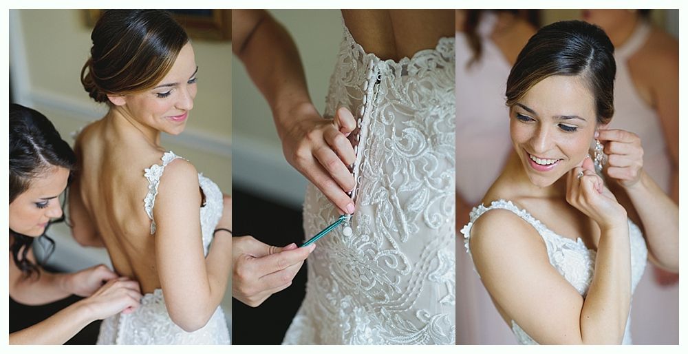 Bride having dress fastened and putting on earrings before wedding.