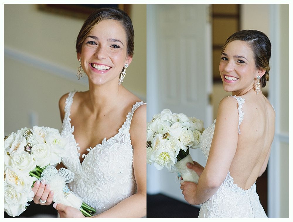 Bride in a white lace wedding dress, smiling, holding a bouquet, in front of a window.