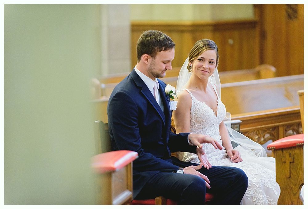 Wedding couple seated in a church, the bride in a white dress, the groom in a suit.