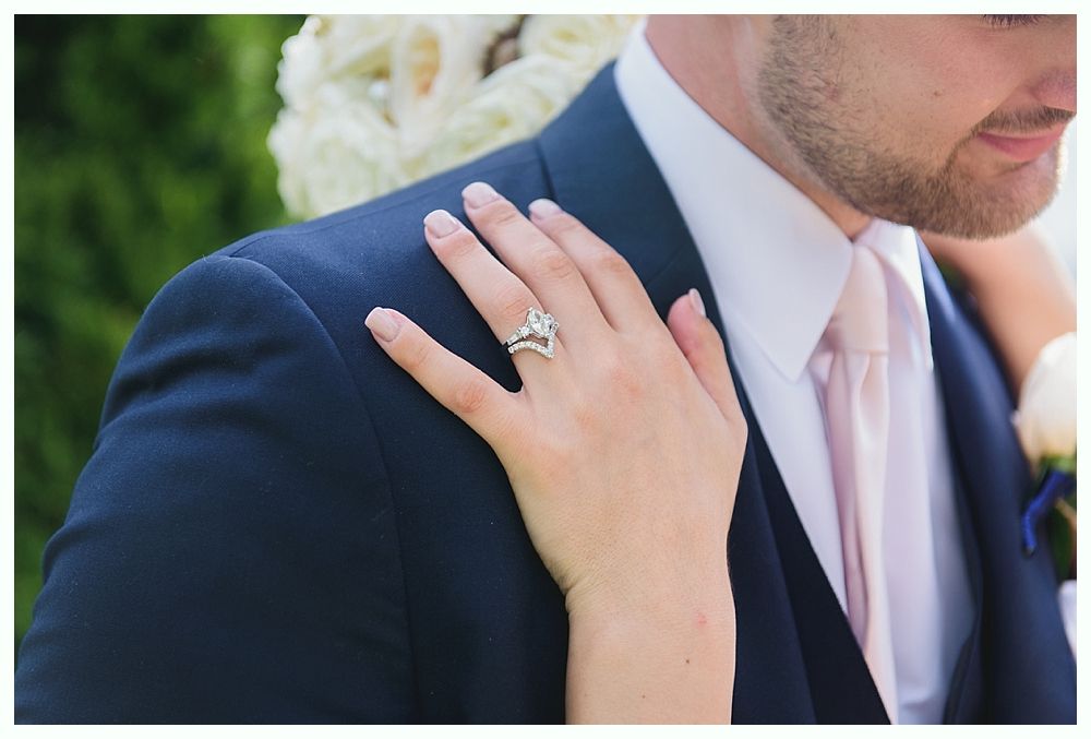 Woman's hand with engagement ring on man's suit jacket.