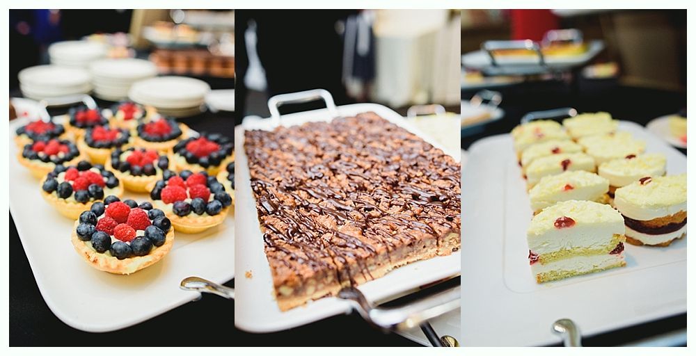 Dessert buffet: tarts with berries, brownie, and layered cakes on white platters.