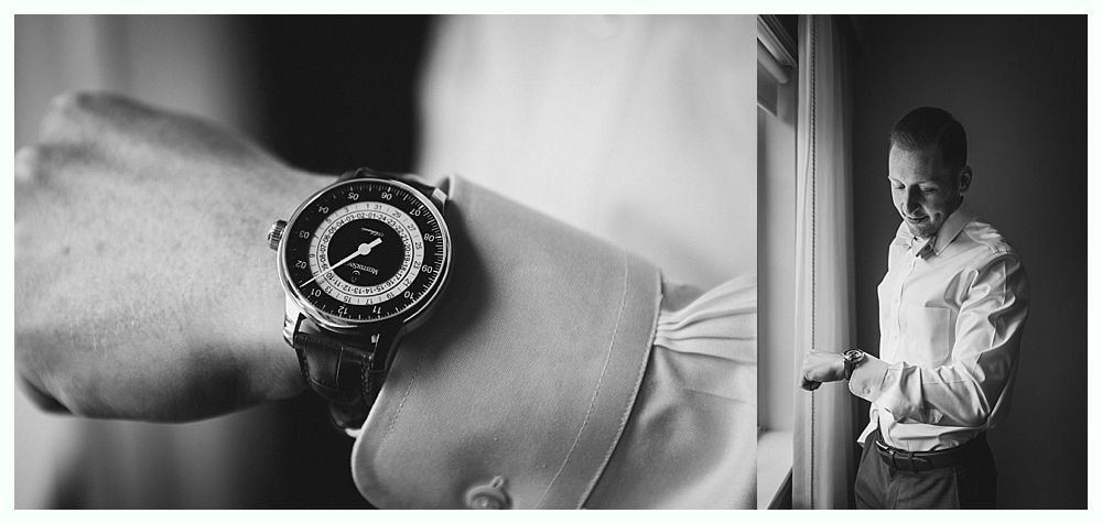 Man wearing a wristwatch, adjusting shirt sleeves near a window, black and white.