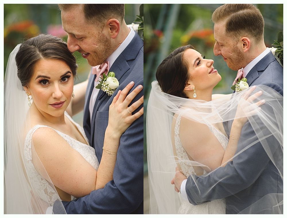 Bride and groom in embrace; the bride gazes at the camera while the groom holds her. Soft background of greenery.