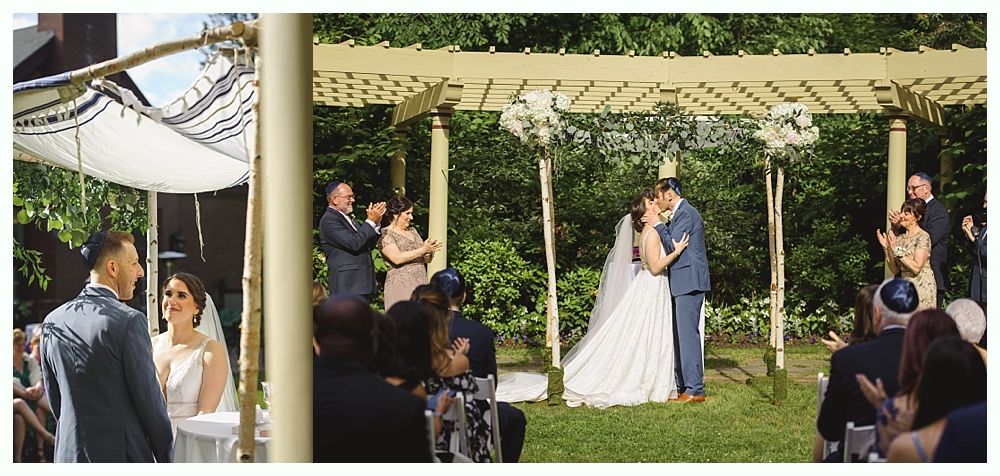 A wedding ceremony: bride and groom kissing under a chuppah, guests clapping in a garden setting.