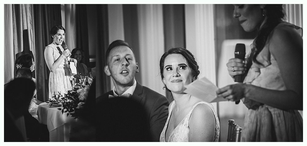 Man in formal wear doing a handstand on a wooden dance floor, guests watching.