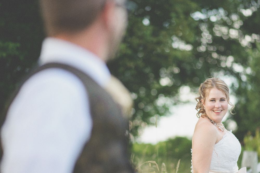 Bride and groom embracing, silhouetted under a large tree, in black and white.