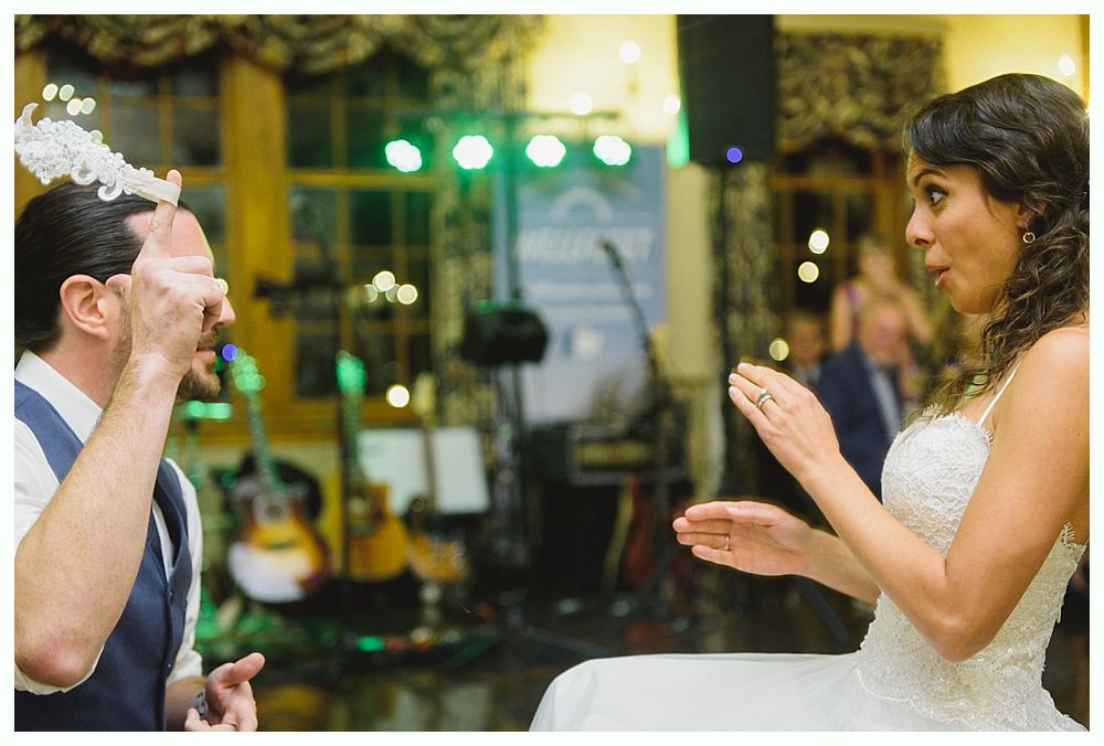 Bride feeding cake to groom blindfolded at a wedding reception.
