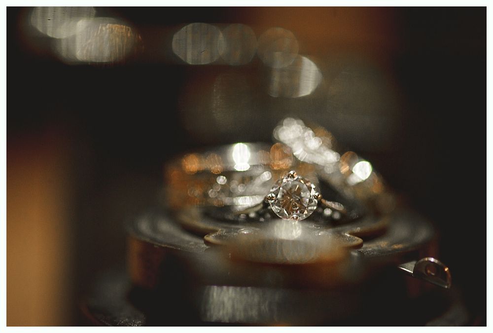 Wedding rings stacked, focus on diamond solitaire with blurred background.