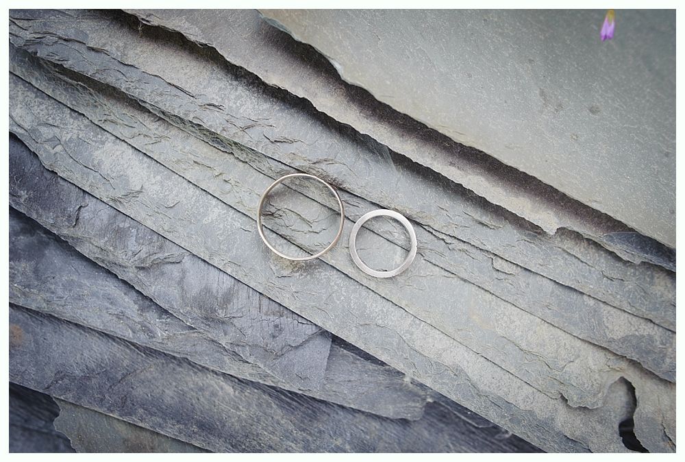 Two silver rings on layered grey stone.