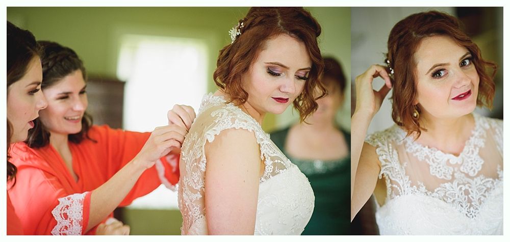 Bride has dress buttoned, smiles. Bridesmaids help, one in red.
