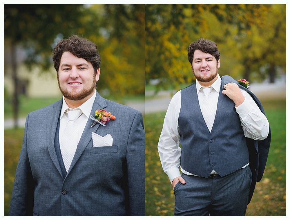 Man in gray suit with boutonniere and white tie, smiles outdoors. Holding jacket over shoulder.