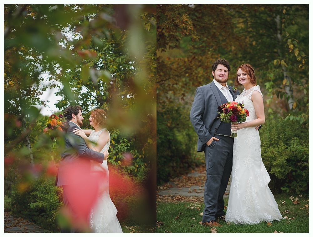 Wedding couple posing outdoors. Man in gray suit, woman in white dress holding bouquet. Fall foliage.