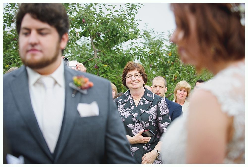 Wedding ceremony: Bride and groom facing each other, guests smiling in background.