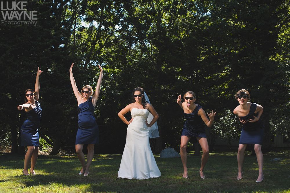 Bride and bridesmaids in sunglasses jumping on grass.