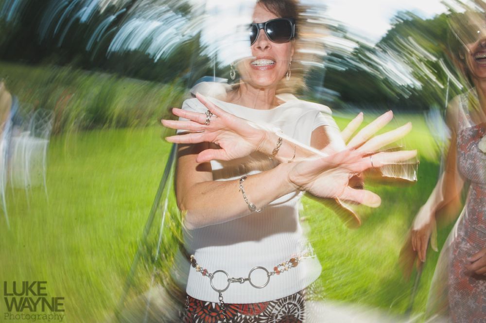 Woman dancing outdoors with blurred motion effect. She wears sunglasses, a white top, and a belt.