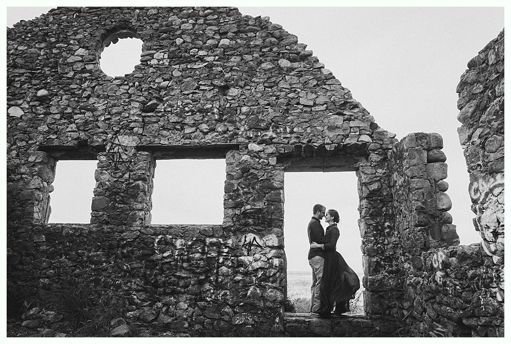 Couple embracing in doorway of stone ruins.