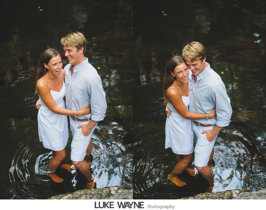 Couple in white clothing embrace in water, smiling.