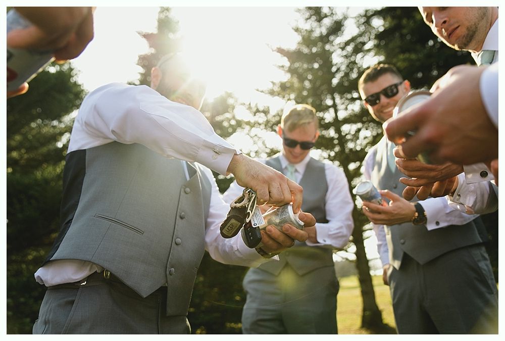 Men in vests opening cans outdoors, sunlit.