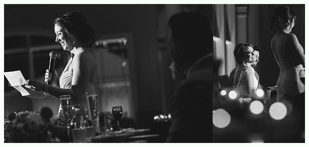 Woman giving a speech at a wedding, holding a microphone and papers. Other guests are nearby.