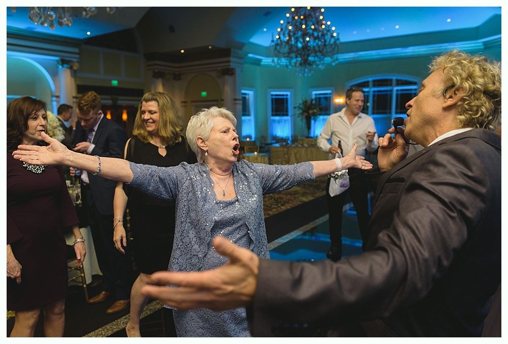 People dancing at a party: a singer with a microphone and a woman singing with arms outstretched. Blue lighting.