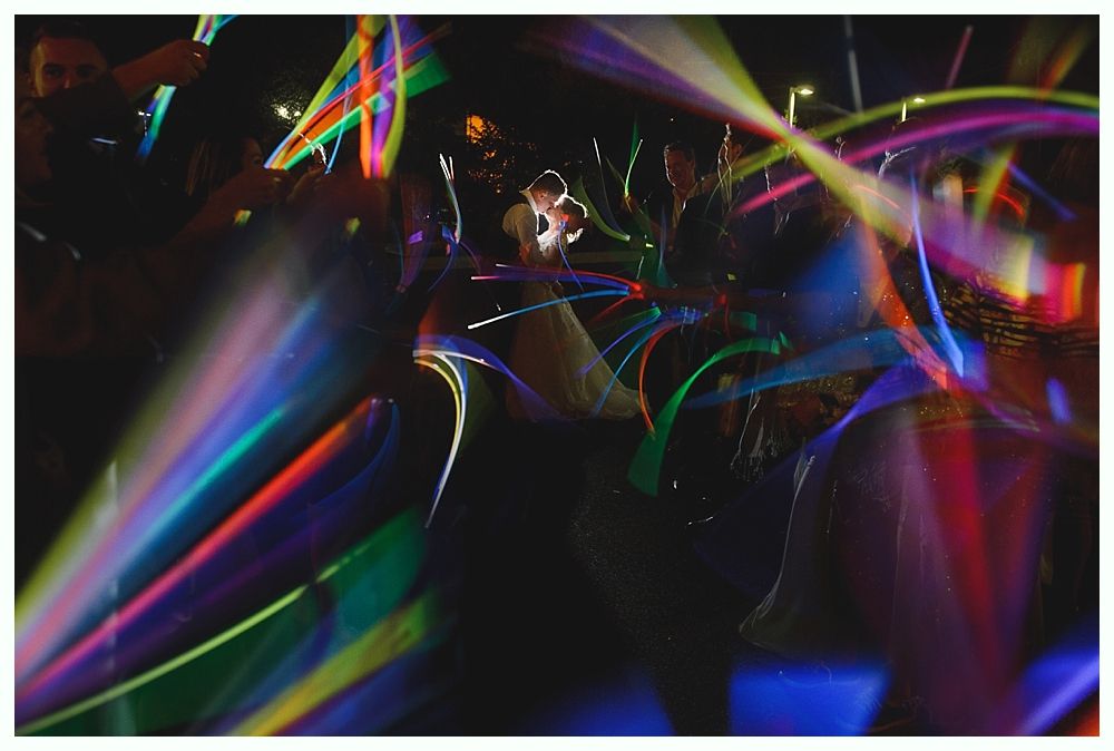 People dancing with colorful light sticks at a nighttime event.
