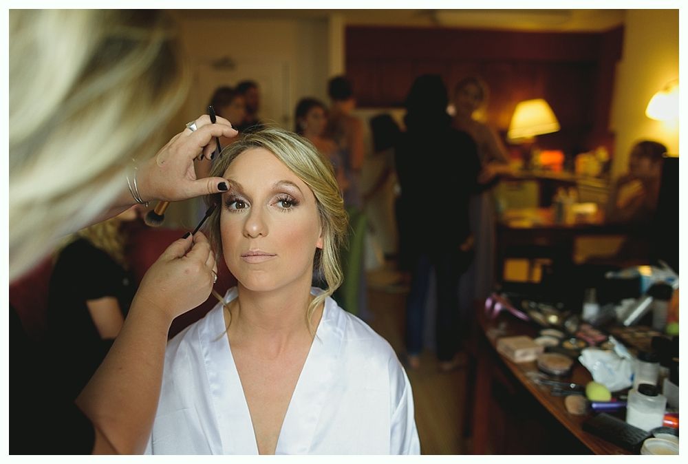 Woman in floral robe smiles; bridesmaids in blue robes on a bed.