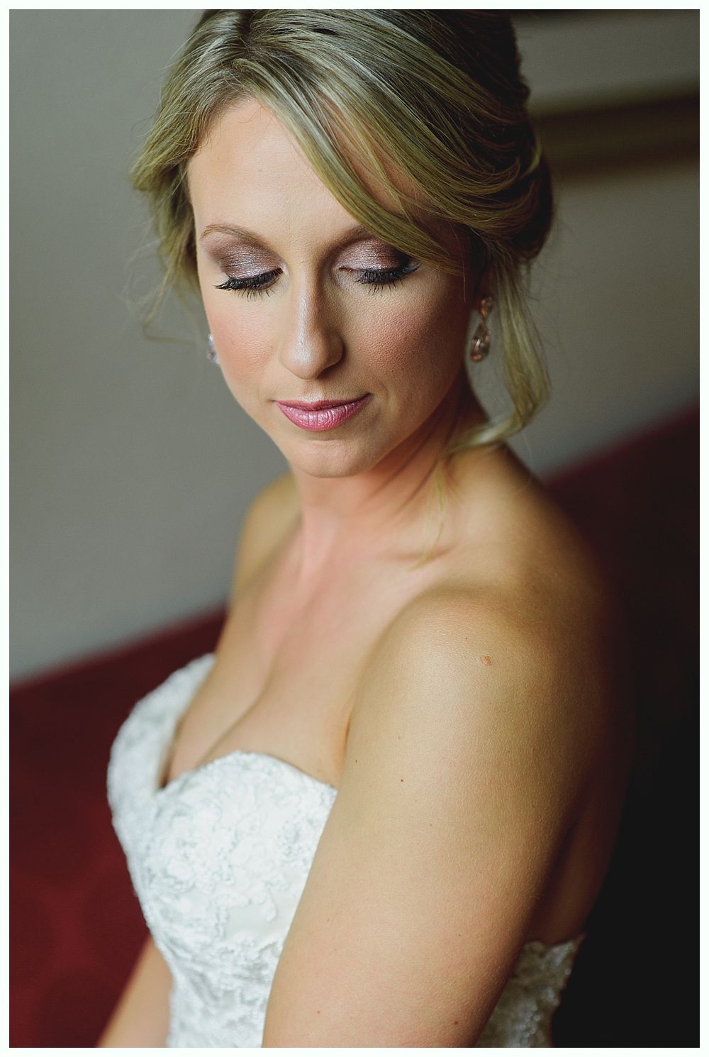 Bride holding bouquet, smiling, wearing white dress with lace, veil, floral crown.