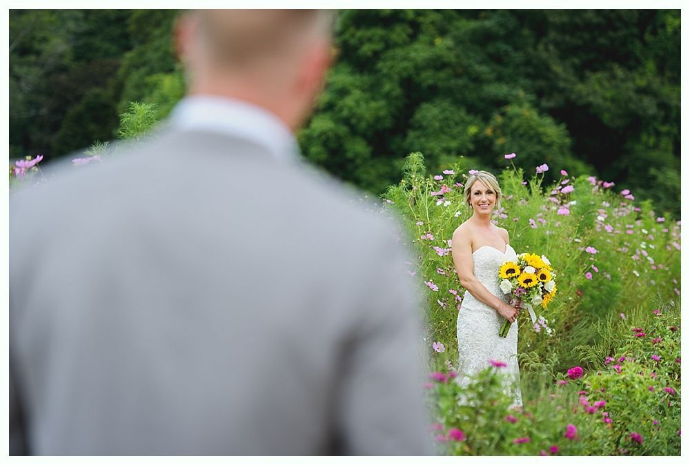 Couple in wedding attire embrace in front of an old, sunlit building.