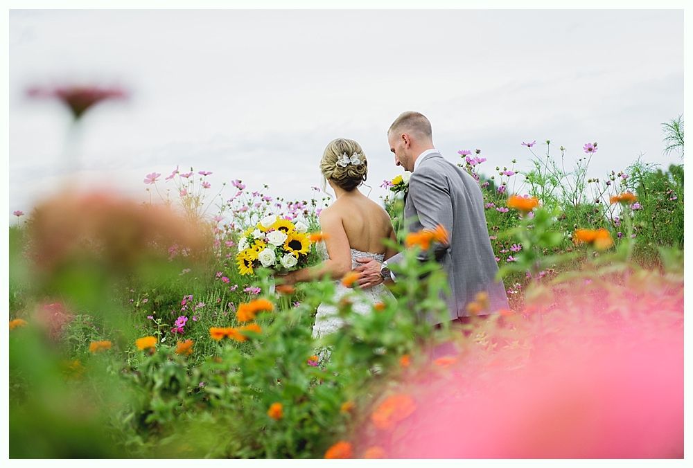 Black and white wedding photo of a couple kissing and then smiling together amongst greenery.