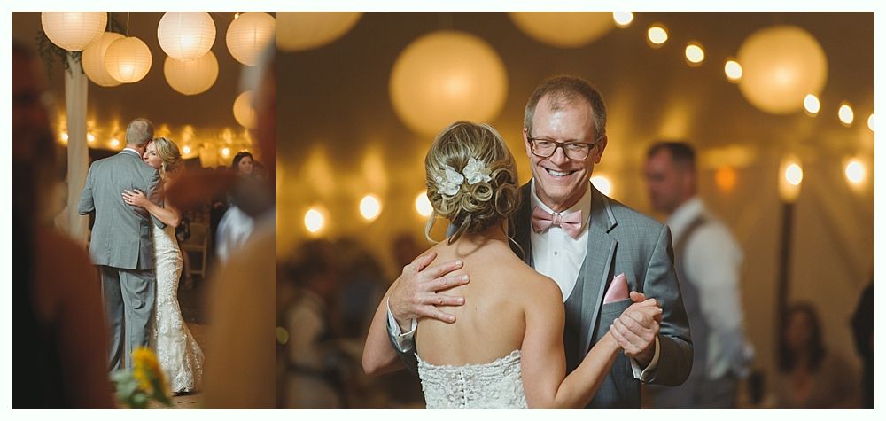 Bride and groom kissing, surrounded by guests at a wedding reception with tables, and a chandelier in a decorated ballroom.