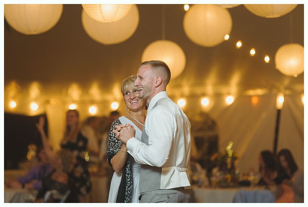 Wedding party celebrating with confetti, couple kissing. Nighttime, trees and road in the background.