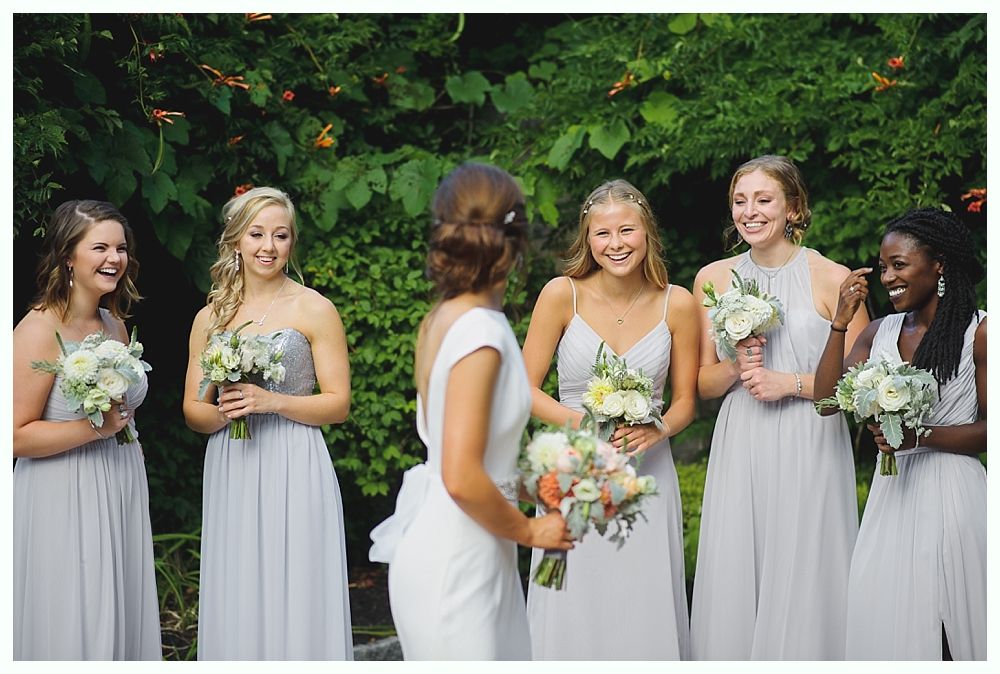 Bride in white gown holding bouquet, posed outdoors. Sunlight streams through trees.