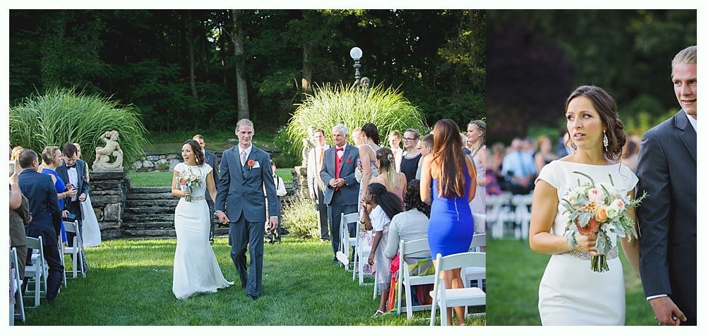 Bride with arms up, making a funny face, groom looking at his hand, cake cutting in background.
