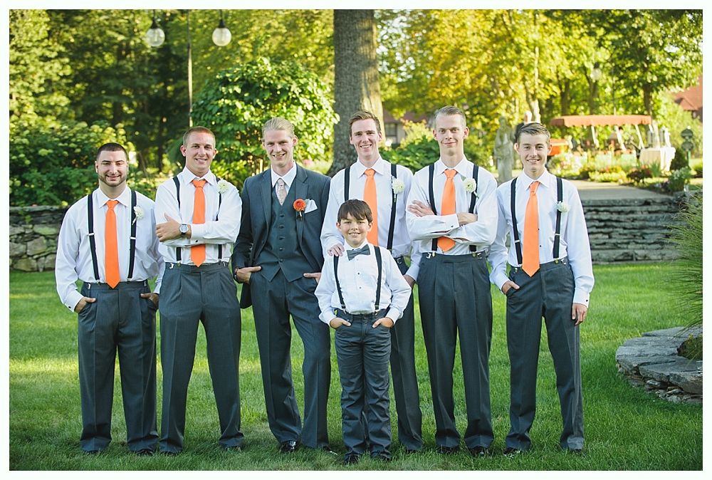 Bride with arms up, making a funny face, groom looking at his hand, cake cutting in background.