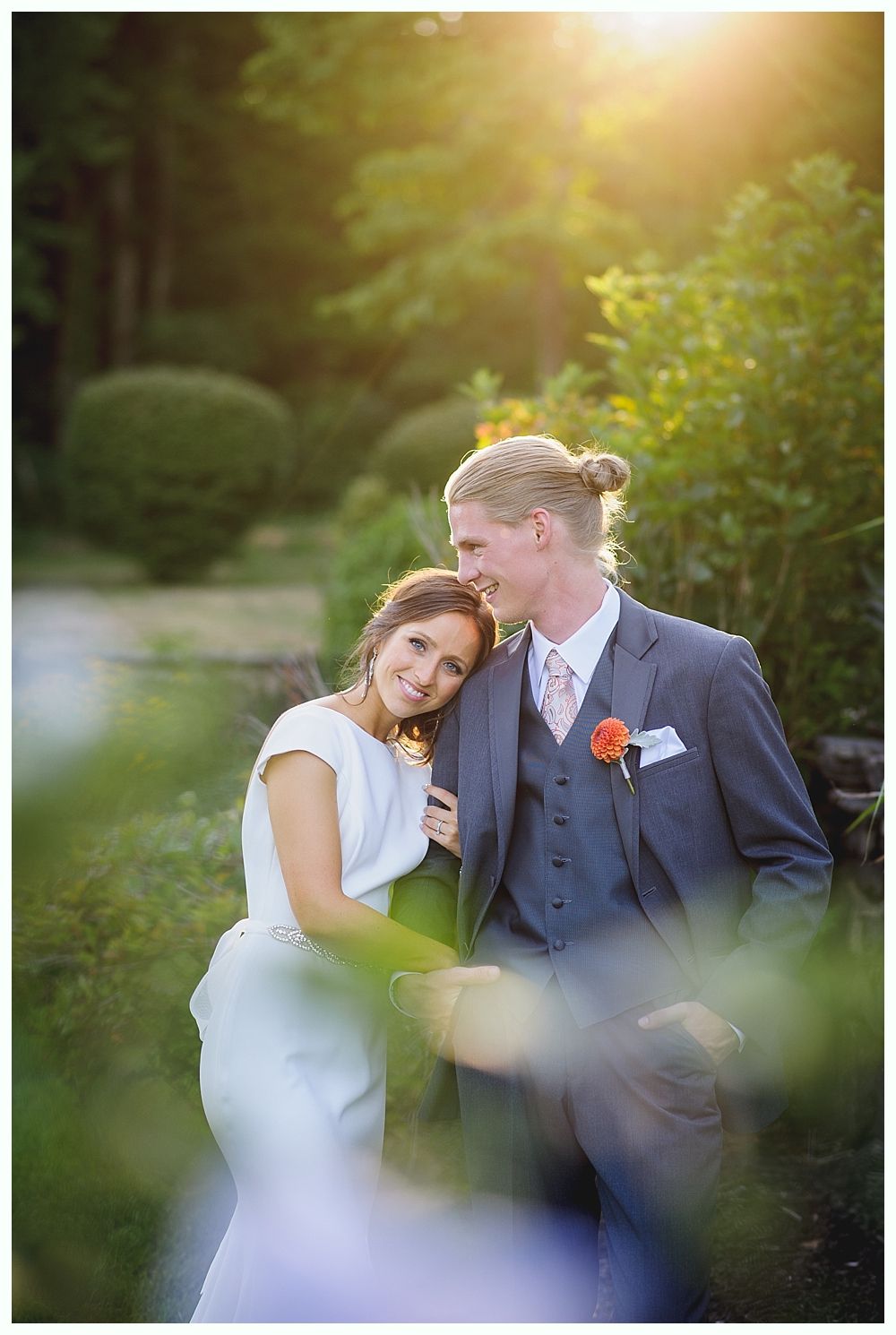 Bride with arms up, making a funny face, groom looking at his hand, cake cutting in background.