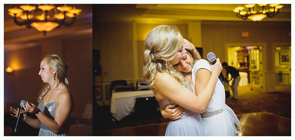 Bride with arms up, making a funny face, groom looking at his hand, cake cutting in background.