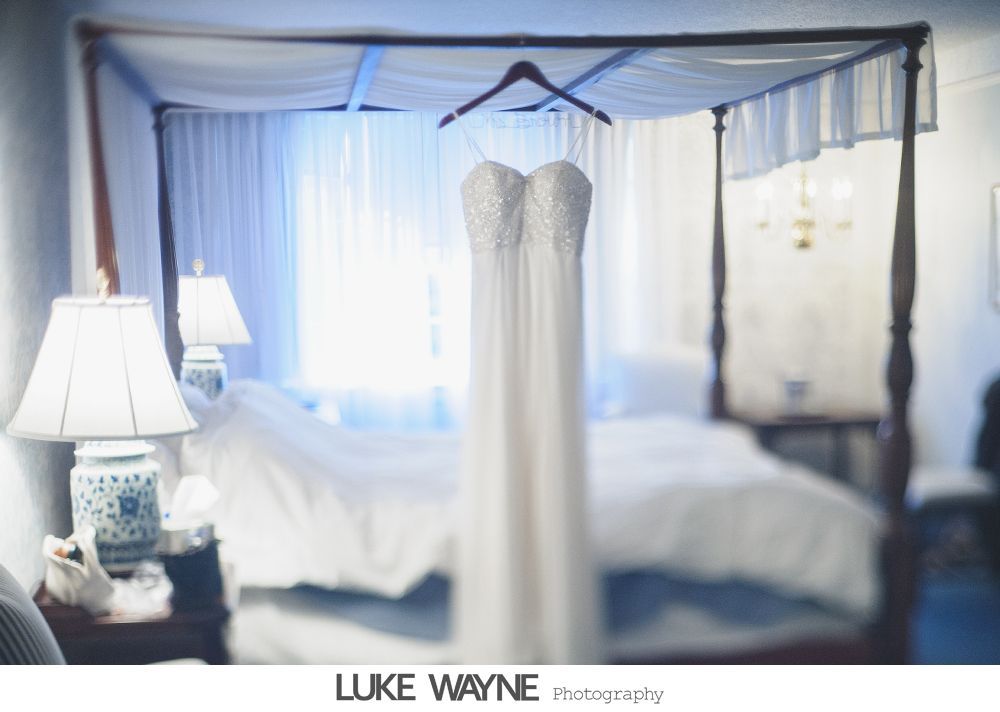 Wedding rings, bouquet, and embellished shoes arranged on dark blue fabric.