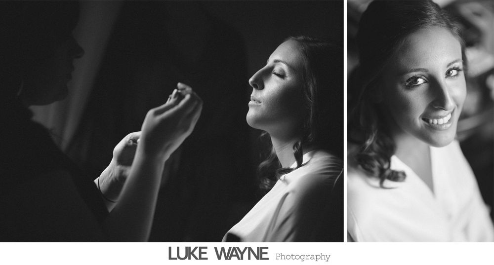 Two wedding dresses hanging in a window, with a chandelier and flowing fabric.