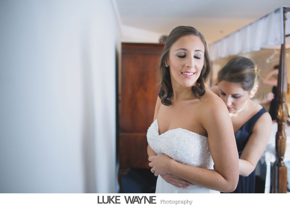 Woman in a button-down shirt adjusts a headpiece, looking at her reflection in a mirror. Black and white photo.