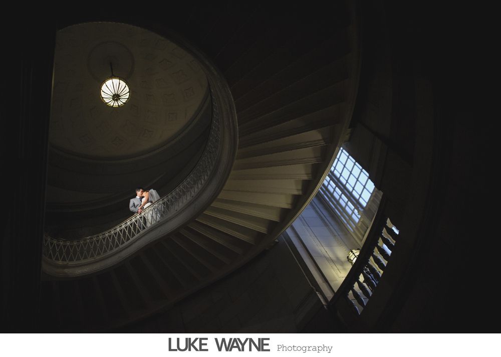 Wedding party in purple and gray outfits posing outdoors in front of city buildings.