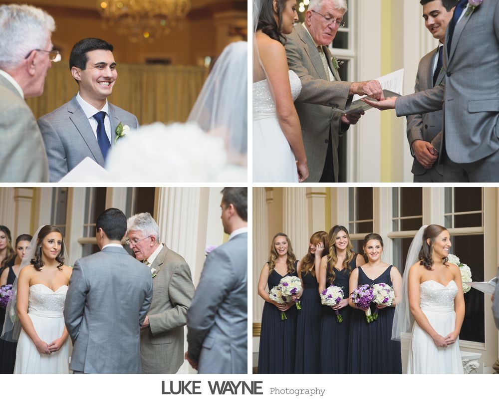 Silhouetted wedding couple and officiant in front of an arched window.