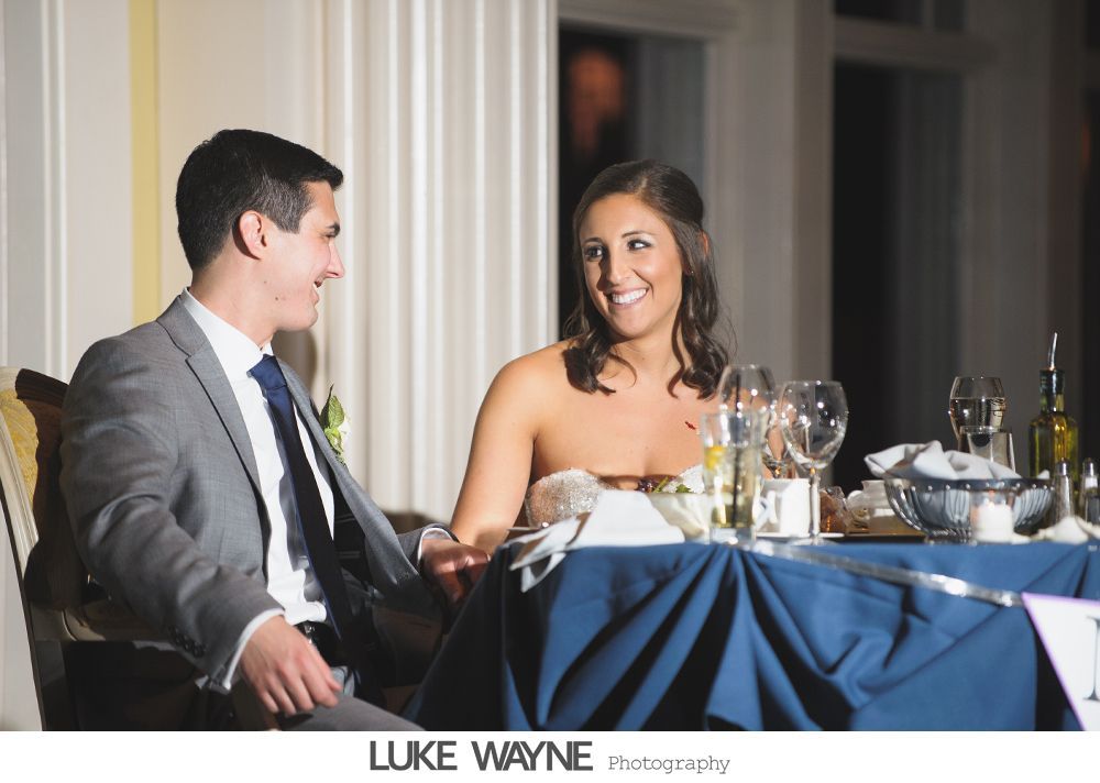 Wedding reception details: cake, flowers, wine, purple and white decor.