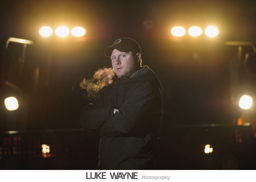 Wedding party in purple and gray outfits posing outdoors in front of city buildings.