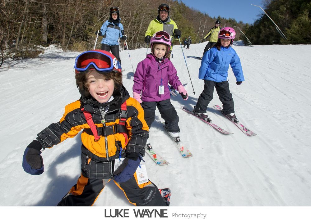 Bride in a fluffy white dress at a bar, smiling. Dark interior, fluorescent lights.