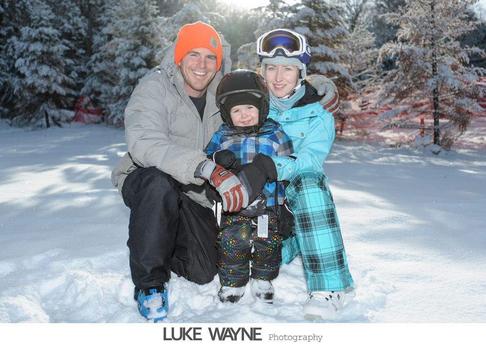 Couple in wedding attire embrace by open school bus door under a sunny sky.
