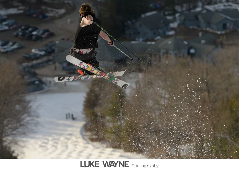 People dancing in a sunlit room; a couple embraces on the dance floor, others watch.