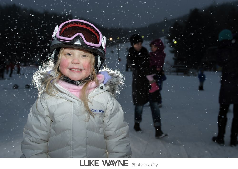 Woman in purple dress giving a speech at a wedding, bride and groom seated at table.