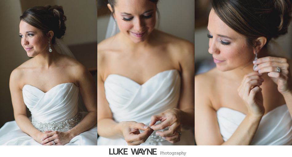Bride in white strapless dress, putting on earrings, smiling softly, with updo hairstyle.