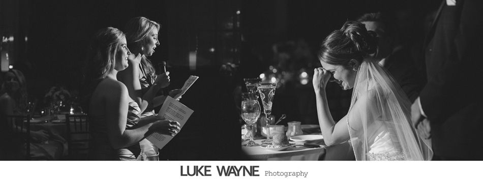 Bride wiping tears at reception, guests seated, dimly lit.